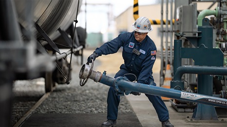 A worker preparing to fill a tank car on the train tracks at the El Segundo refinery.